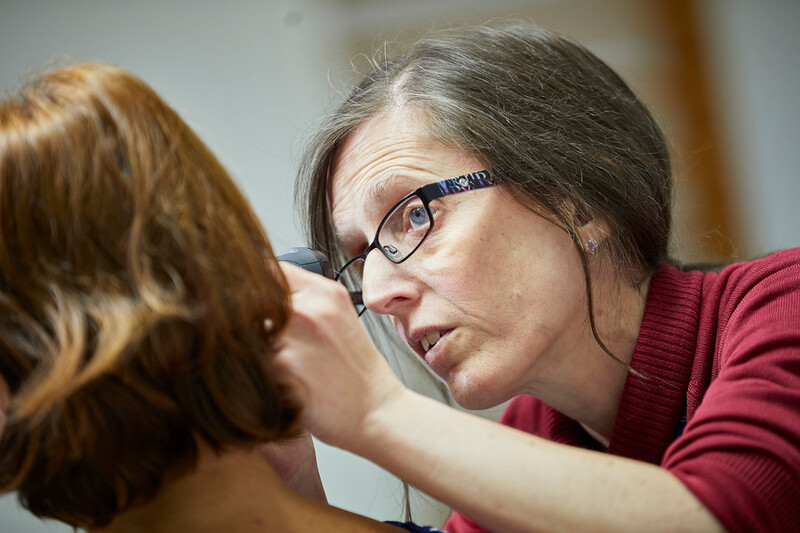 A hearing specialist checking a patient's ear