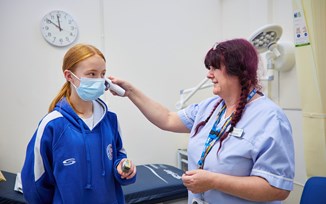 A nurse taking the temperature of a child
