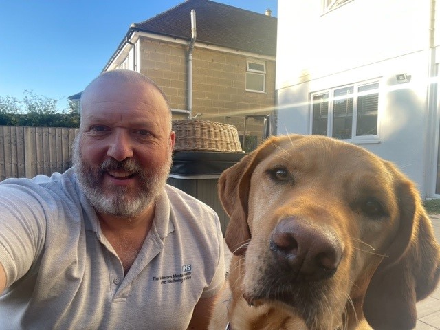 Jon, our armed forces lead, takes a selfie outside on a sunny day with Baxter his assistance dog
