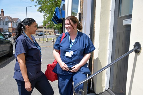 Two NHS workers in uniform stood talking to each other outside