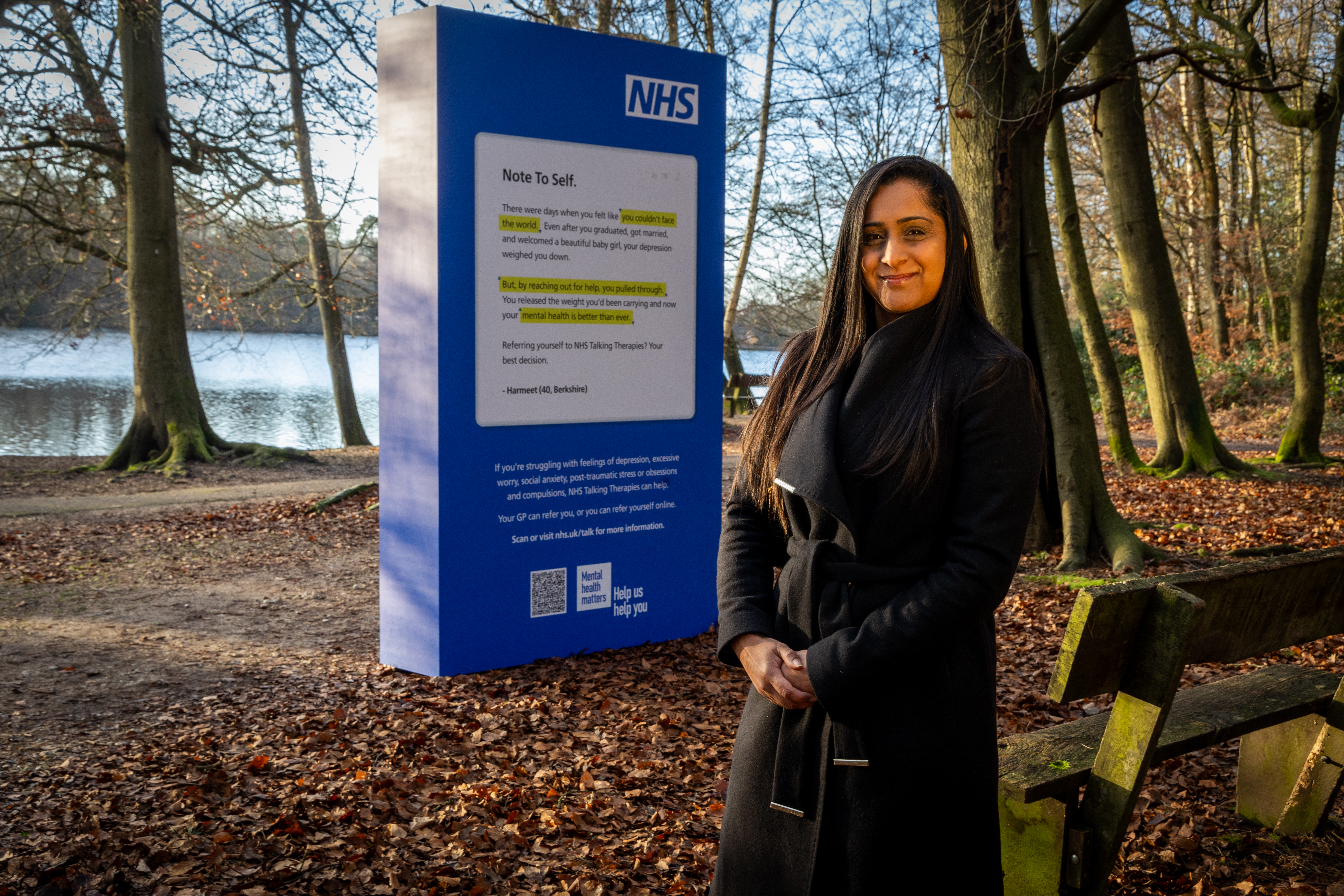 Harmeet stands in front of the NHS Talking Therapies public display in Black Park