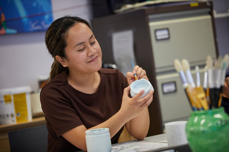 A person relaxing, by painting a cup