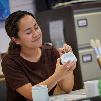 A person relaxing, by painting a cup