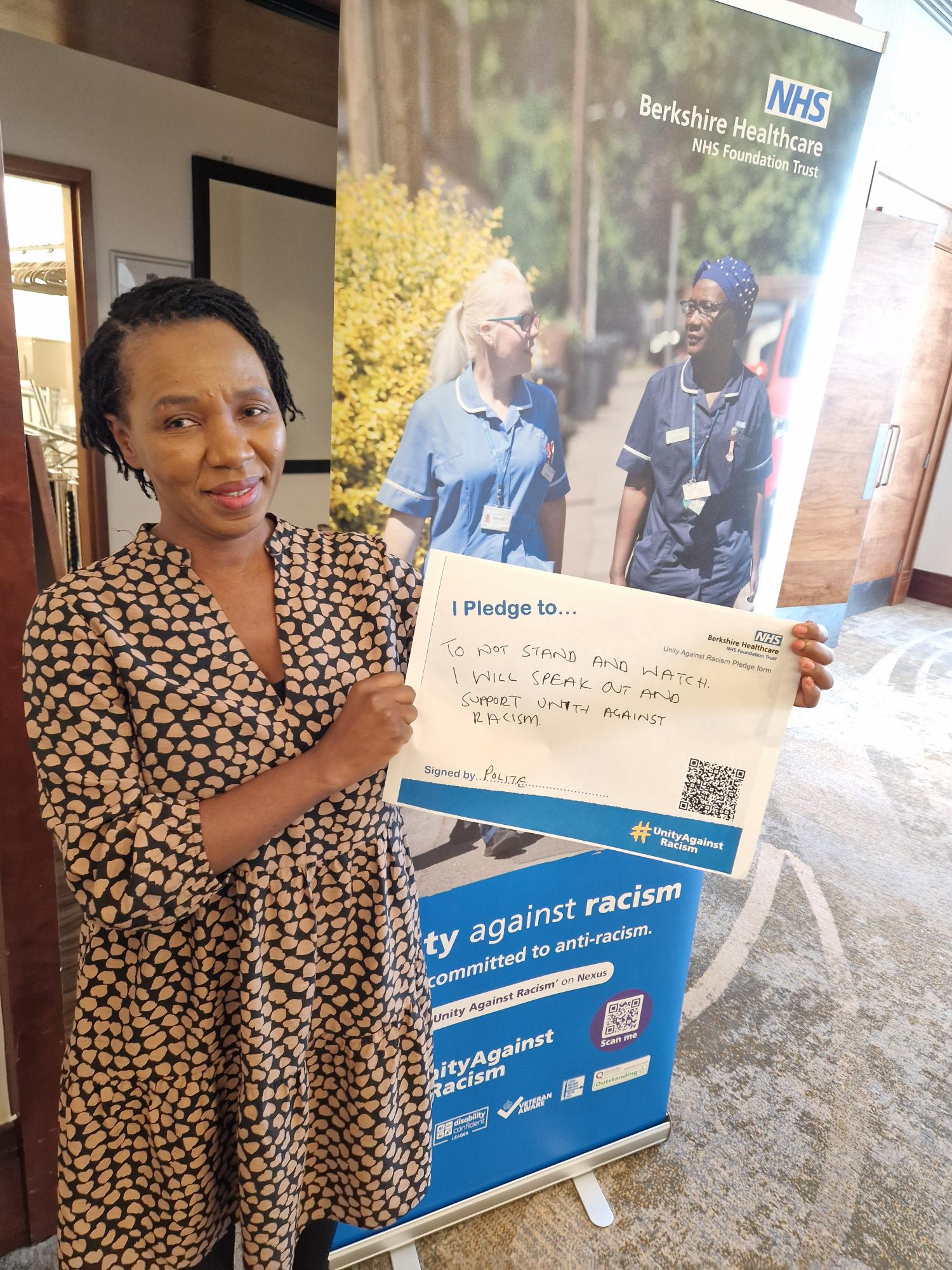 A photo of a woman holding her pledge against racism