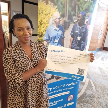 A photo of a woman holding her pledge against racism