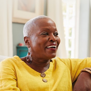 A photo of a woman smiling wearing a yellow top