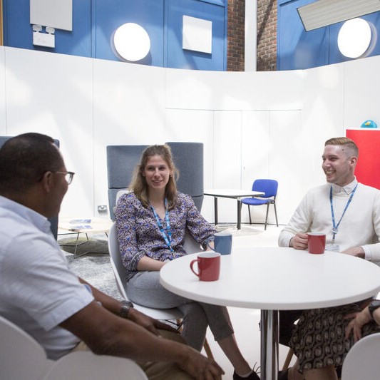 Two people sat, drinking a cup of tea, while reading a leaflet about onboarding