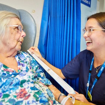 A staff member talking to a patient bedside