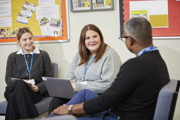 Two Happy Female Staff Talking To Male Staff