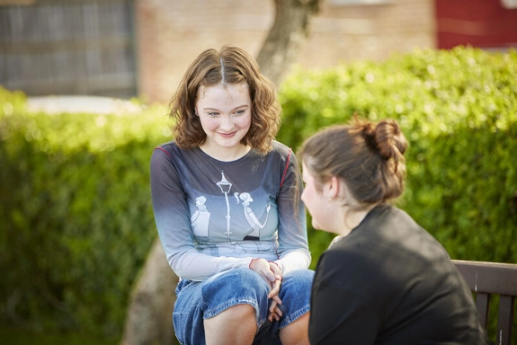 Two Young People Sitting On A Bench