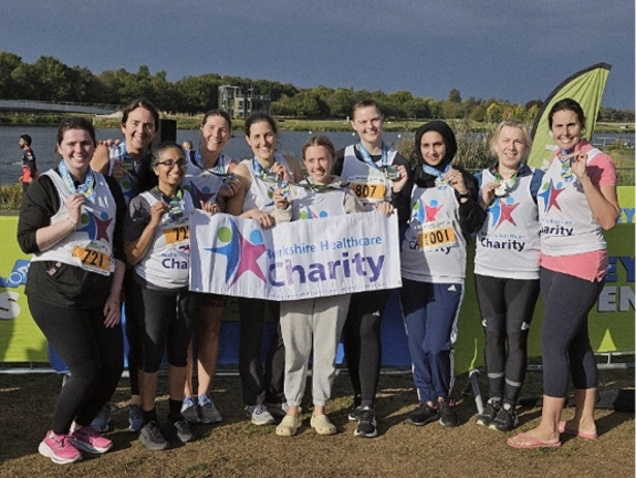 A group photo of 10 staff, holding their medals and the Berkshire Healthcare Charity banner
