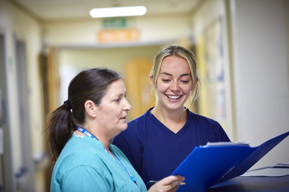 Two staff looking at a folder in corridor